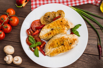 Chicken fillet grilled with vegetables. Wooden background. Top view