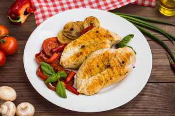 Chicken fillet grilled with vegetables. Wooden background. Top view