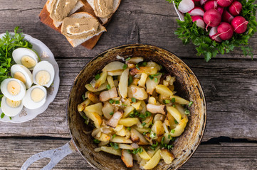 Fried potatoes in lard with herbs on an old wooden table. Top view. Close-up