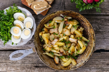 Fried potatoes in lard with herbs on an old wooden table. Top view. Close-up