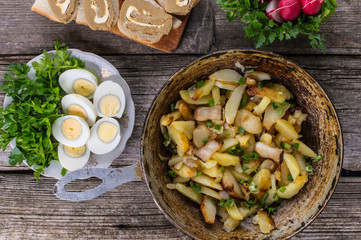 Fried potatoes in lard with herbs on an old wooden table. Top view. Close-up