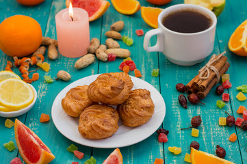 Obraz na płótnie Canvas Custard pastries with coffee and sweets different fruits. Cute fabulous breakfast. Turquoise wooden background.