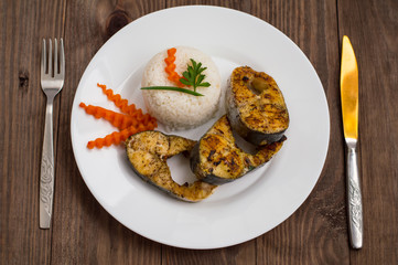 Fried fish steak with boiled rice and carrots. Top view. Close-up