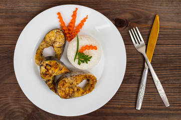 Fried fish steak with boiled rice and carrots. Top view. Close-up