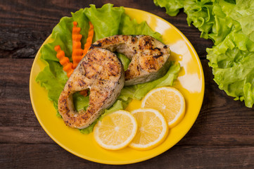 Fish grilled with lemon. Top view. Wooden background. Close-up