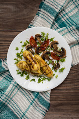 Zrazy Potato stuffed with meat  mushrooms and grilled tomatoes on a white plate. Wooden background. Top view. Close-up