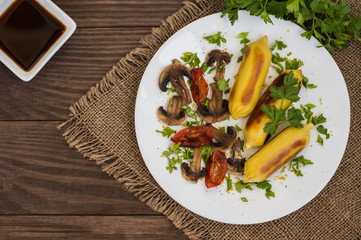 Zrazy Potato stuffed with meat  mushrooms and grilled tomatoes on a white plate. Wooden background. Top view. Close-up