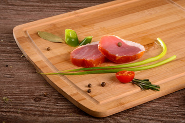 Sirloin smoked sliced piece rests on a wooden Board,lay next to fresh vegetables