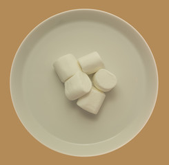 Süße Marshmallows auf weissem Teller - Freisteller mit braunem Hintergrund