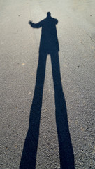 Shadow of a long man on asphalt