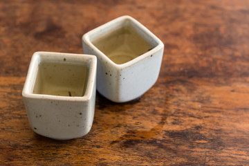 Chinese green tea in square white teacups on a wooden table