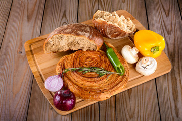 the broken bread on the Board next to olive oil and vegetables