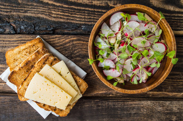 Salad with radishes, apples, greens and a sandwich  fish pate. Wooden background. Top view. Close-up