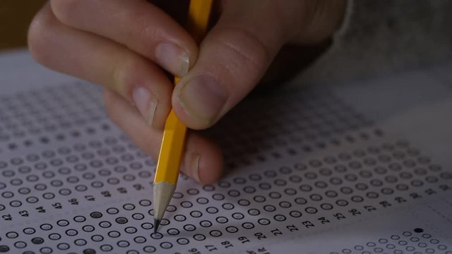 4K Young female marking her test answers on paper with a pencil