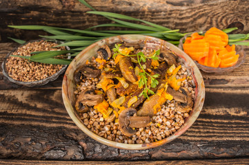 Buckwheat porridge with meat and mushrooms on wooden rustic background. Top view. Close-up