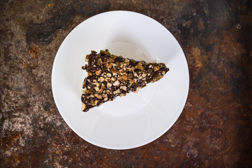 Napoleon cake covered with chocolate and walnuts  raisins on an old table. Top view. Close-up