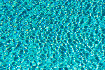 Turquoise water surface full of ripples, waves and light spots