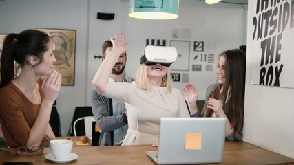 first experience with virtual reality glasses young team supports young beautiful blond girl in modern startup office