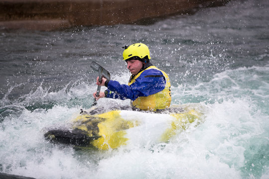 Man in kayak paddling hard in rough water