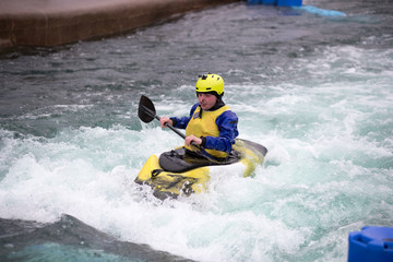 Man in kayak paddling upstream in fast flowing water