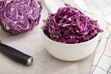 Shredded red cabbage in clay bowl on stone background. Vegetaria