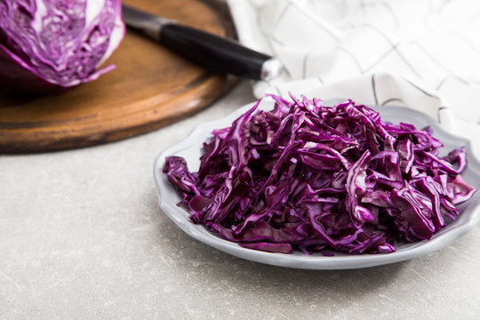 Shredded red cabbage in clay bowl on stone background. Vegetaria
