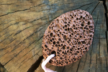 pumice stone with a cord on old wooden background