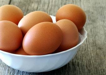 brown eggs in white bowl on a wooden table