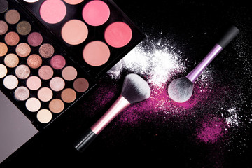 Colorful makeup palette and brush to apply powder. on pure black background. 