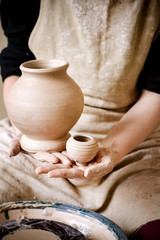 Sculpt Man potter holds palms just made pitchers of different sizes. Potter holds made pots....