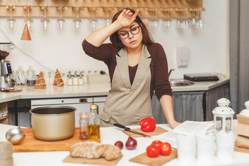 Young brunette housewife in the kitchen is tired cooking tomato soup.