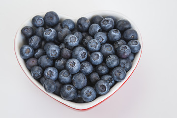 Blueberries in bowl in form of heart on white background
