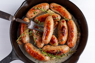 Home-made Pork Sausages in rustic pan with thyme