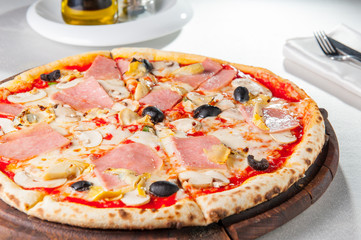 Selective focus Close up Delicious Meat Pizza with bacon, chicken fillet, sliced mushrooms and olives on the wooden board on the served restaurant table