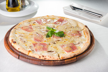 Selective focus Close up Delicious Pizza with bacon, sliced mushrooms and cream cheese on the wooden board on the served restaurant table