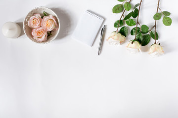 White desk with roses. Top view, flat lay