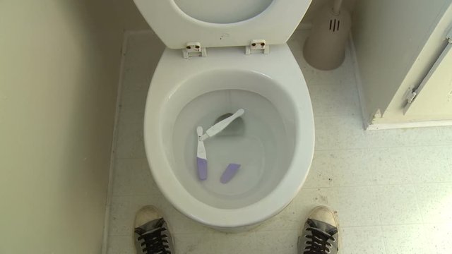 Toilet Pregnancy Test. Funny static point of view (POV) shot of a person standing above a toilet as a home pregnancy test is unceremoniously tossed into the water.