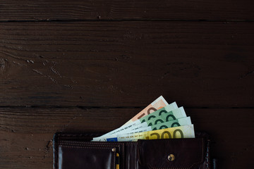 Euro cash. Open brown male wallet with Euro banknotes on wooden background with copy space for your design