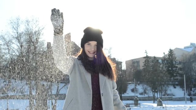 young woman throws snow