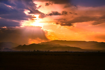Landscape of beautiful  mountains painted in sunset colors and covered dramatic sky with bright clouds.