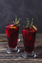 Two glasses of hot mulled wine on a dark background. Spices, oranges and fir cones