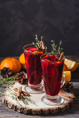 Two glasses of hot mulled wine on a dark background. Spices, oranges and fir cones