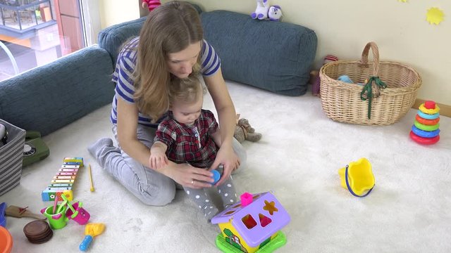 young loving mom teaches daughter girl to distinguish object shapes.