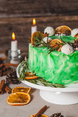 Green sponge cake on a wooden background. Decorated cones, candles, oranges cones, candles, oranges