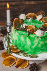 Naklejka na ściany i meble Green sponge cake on a wooden background. Decorated cones, candles, oranges cones, candles, oranges