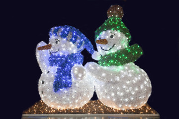 Two funny snowman wave against black night background