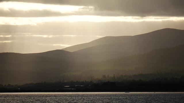 Sun beams (ray of light) to mountains during sunset at Invergordon, Scotland, UK
