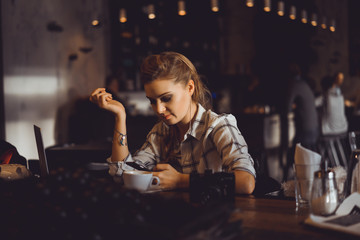 young pretty brunette woman eat chocolate in cafe, using smartphone and laptop touch screen display, sweet food, tasty breakfast, close up portrait, hipster girl, fanny, drink coffee