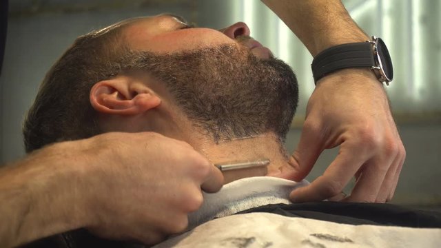 Barberman shaving beard of man