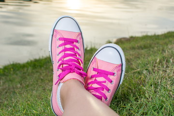 Enjoying by lake. Woman wearing pink sneakers